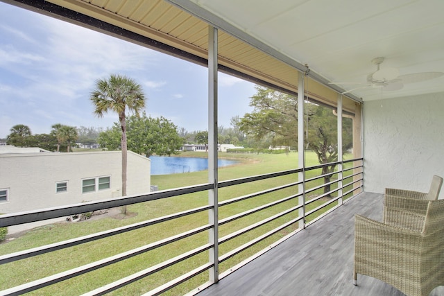 unfurnished sunroom featuring ceiling fan and a water view