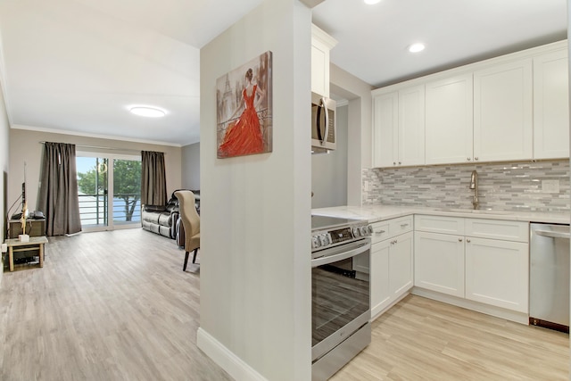 kitchen with stainless steel appliances, white cabinetry, sink, and light hardwood / wood-style flooring