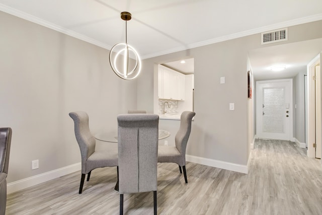 dining area featuring crown molding and light hardwood / wood-style flooring