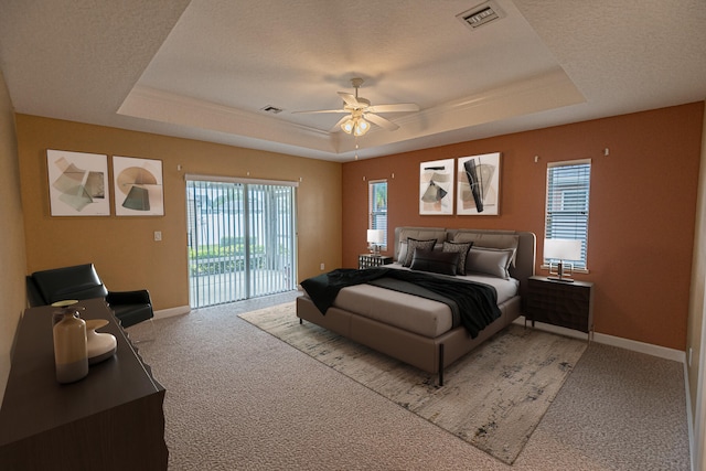 bedroom with carpet floors, access to outside, ceiling fan, and a tray ceiling