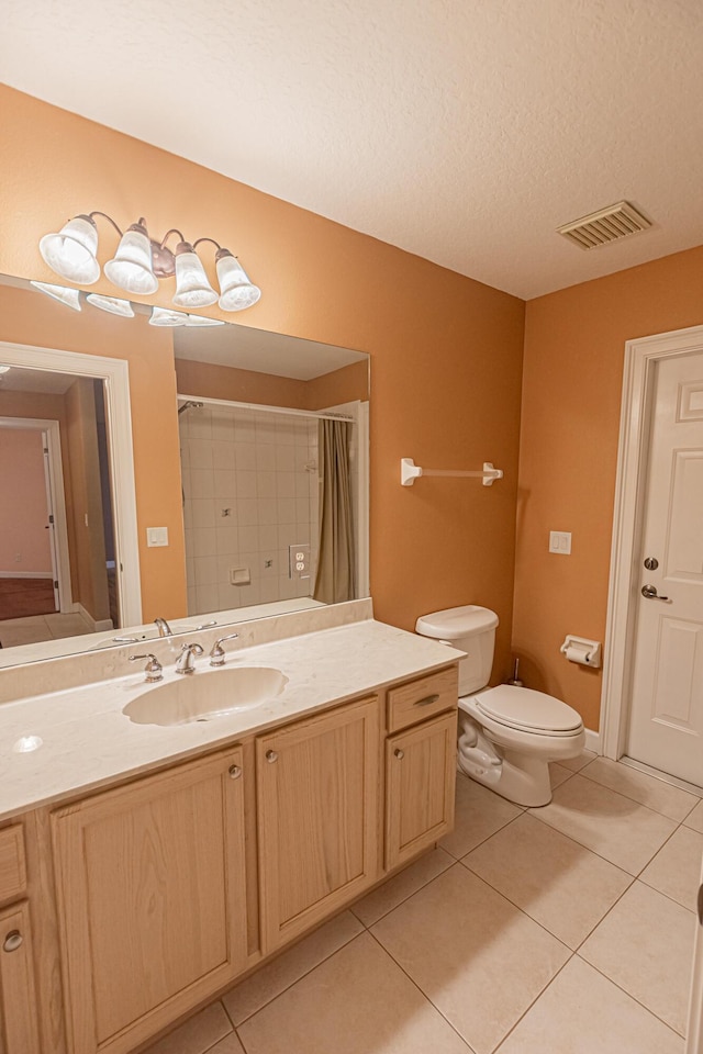 bathroom with tile patterned flooring, vanity, a textured ceiling, toilet, and walk in shower