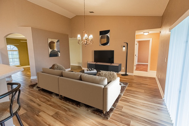 living room with vaulted ceiling, hardwood / wood-style floors, and an inviting chandelier