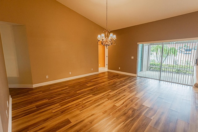 unfurnished room with lofted ceiling, hardwood / wood-style floors, and a chandelier