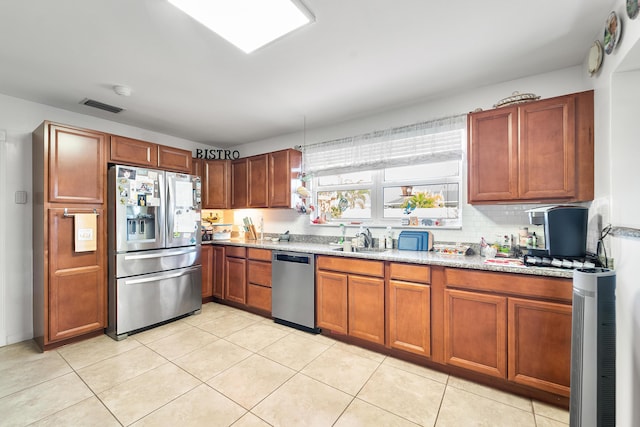 kitchen featuring appliances with stainless steel finishes, light stone countertops, sink, and a wealth of natural light