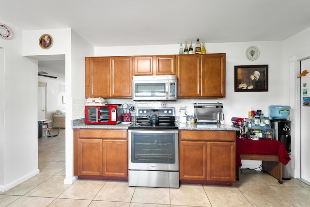 kitchen with light stone counters, stainless steel appliances, light tile patterned flooring, and tasteful backsplash