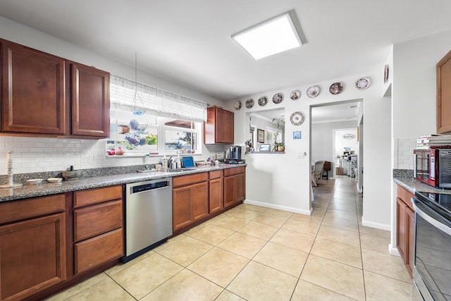 kitchen with stainless steel appliances, tasteful backsplash, sink, and light tile patterned floors