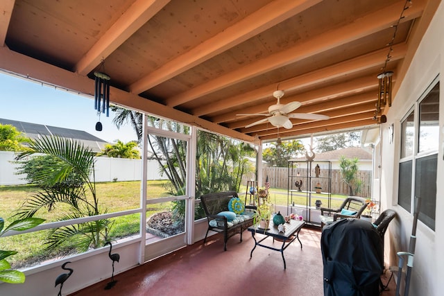 sunroom / solarium featuring beamed ceiling, plenty of natural light, and ceiling fan