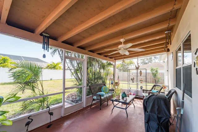 sunroom with a healthy amount of sunlight, beam ceiling, and ceiling fan