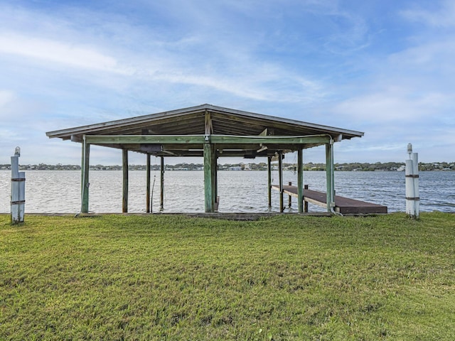 view of dock with a lawn and a water view