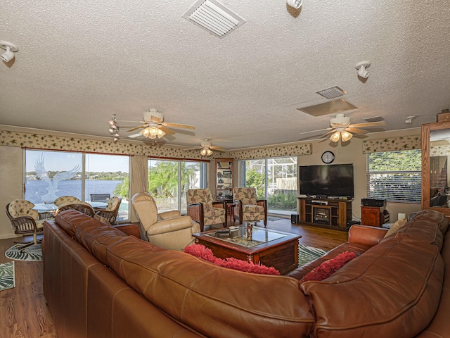 living room featuring a water view, ornamental molding, wood-type flooring, and a textured ceiling