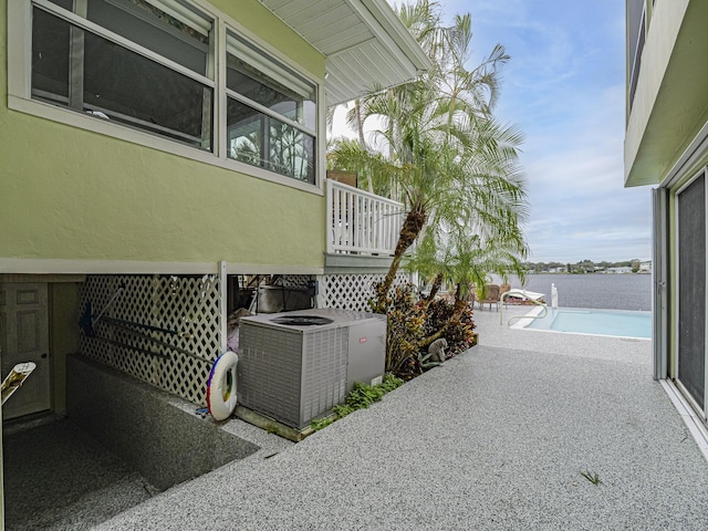 view of patio / terrace featuring central air condition unit, a water view, and an outdoor pool