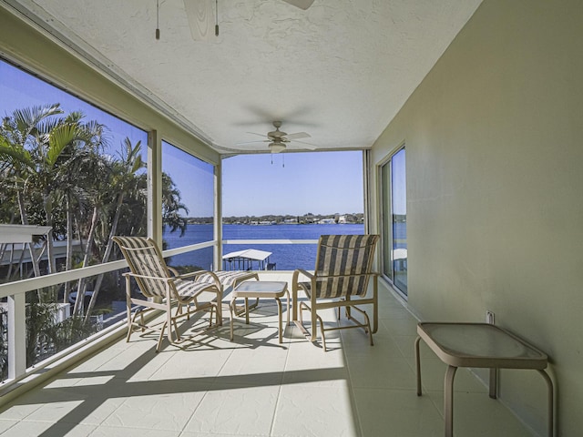 sunroom / solarium featuring a water view and ceiling fan