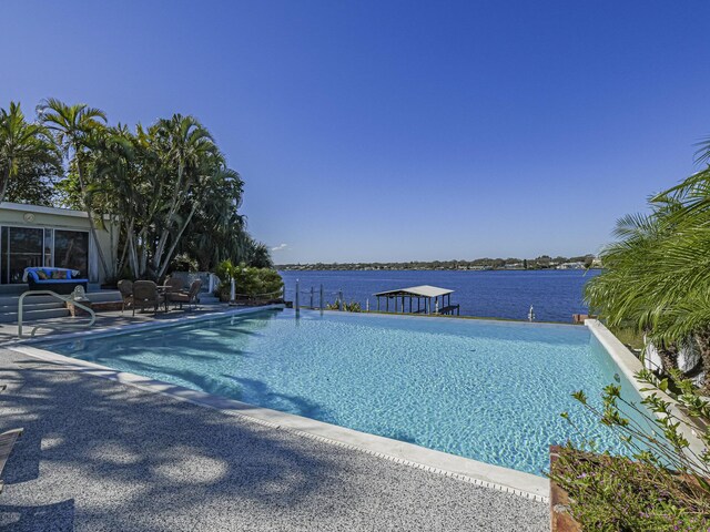 view of swimming pool with a water view and a patio area