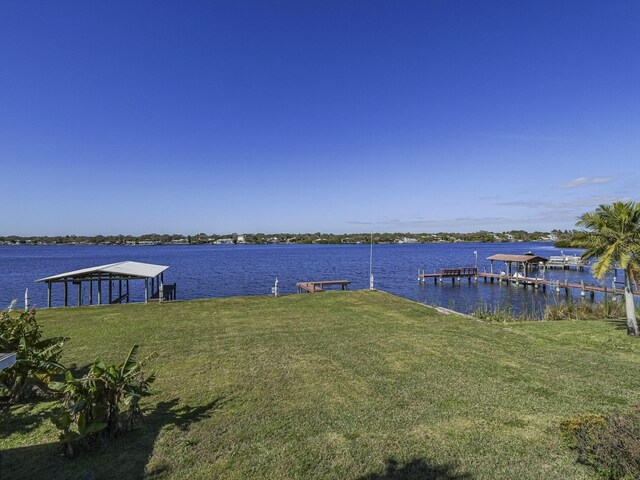 view of dock with a water view and a yard