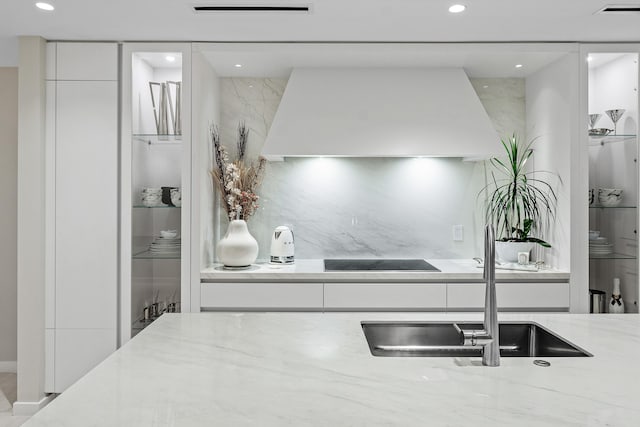 kitchen with white cabinets, custom exhaust hood, light stone counters, and black electric cooktop