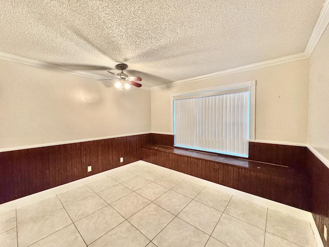 unfurnished room with ornamental molding, wooden walls, ceiling fan, and a textured ceiling