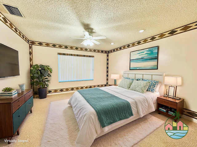 bedroom featuring ceiling fan, light colored carpet, and a textured ceiling