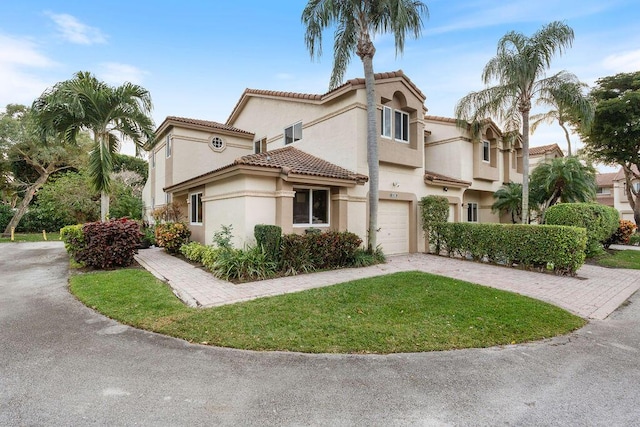 view of front facade featuring an attached garage, a front yard, decorative driveway, and stucco siding