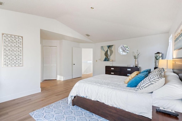 bedroom with light hardwood / wood-style floors, a closet, and lofted ceiling