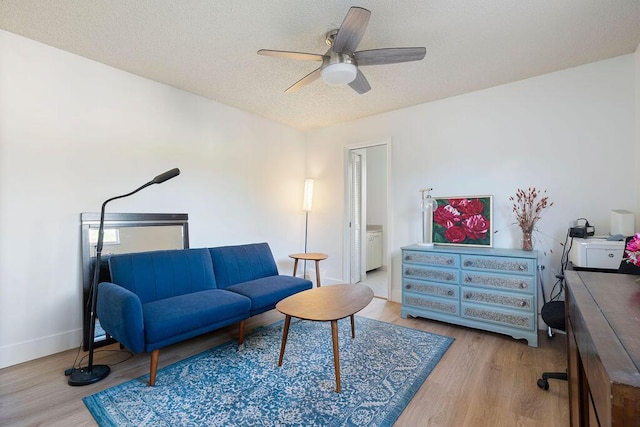 living room with ceiling fan, a textured ceiling, and light hardwood / wood-style flooring