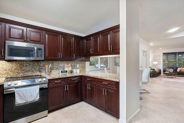 kitchen featuring vaulted ceiling, appliances with stainless steel finishes, light stone counters, light tile patterned flooring, and a textured ceiling