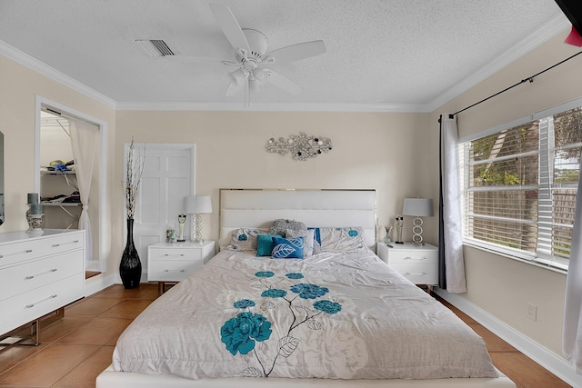 tiled bedroom with ceiling fan, a textured ceiling, and ornamental molding