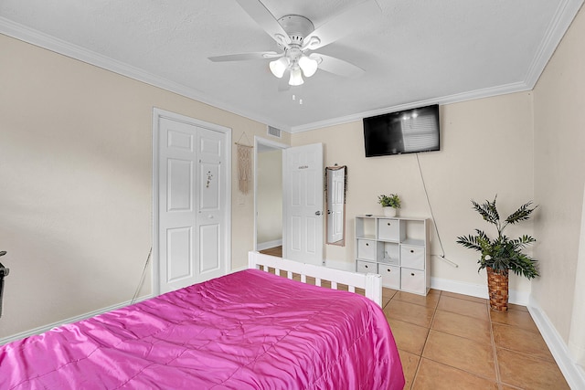 bedroom featuring ceiling fan, tile patterned flooring, a closet, and crown molding