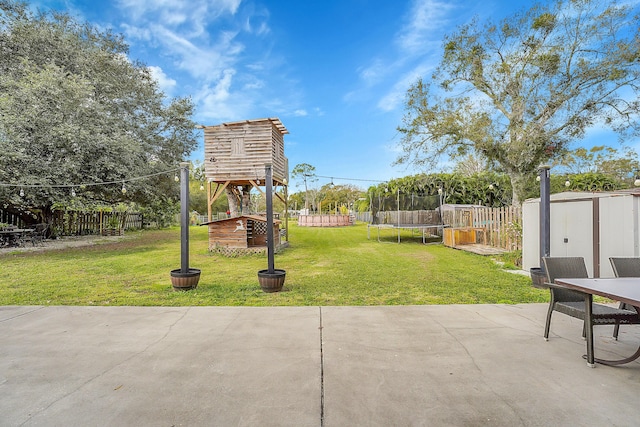 view of yard with a trampoline, a patio area, and a storage unit