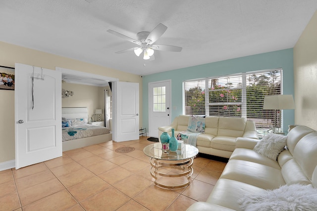 tiled living room featuring ceiling fan, baseboard heating, and a textured ceiling