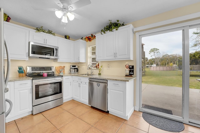 kitchen featuring sink, light tile patterned floors, light stone countertops, stainless steel appliances, and white cabinets