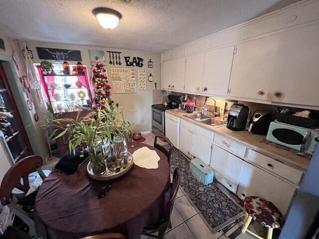 kitchen featuring white dishwasher, sink, white cabinetry, and a textured ceiling