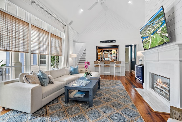 living room featuring ceiling fan, a brick fireplace, dark wood-type flooring, and high vaulted ceiling