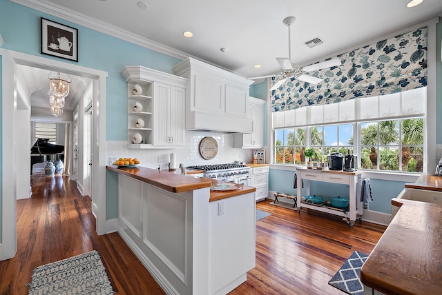 kitchen with stainless steel stove, wooden counters, white cabinets, kitchen peninsula, and dark hardwood / wood-style flooring