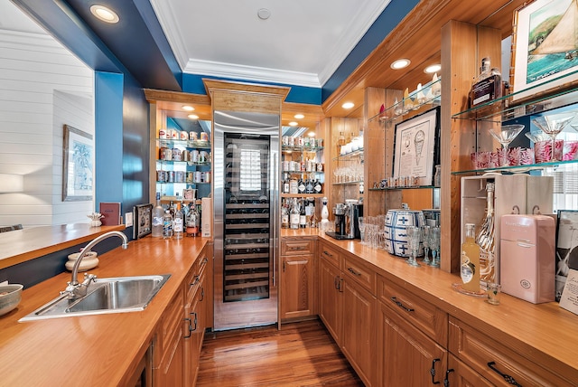 bar featuring sink, wood walls, crown molding, light hardwood / wood-style flooring, and beverage cooler