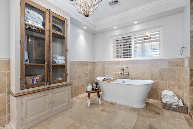 bathroom featuring crown molding, a tub, a notable chandelier, and tile walls