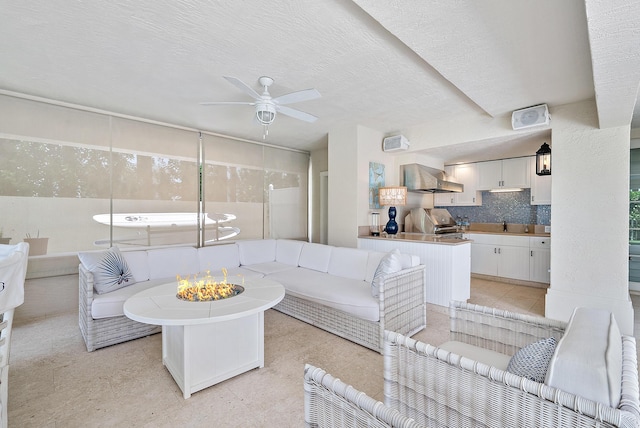 living room featuring ceiling fan and a textured ceiling