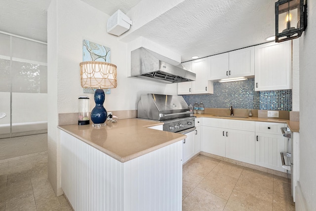 kitchen with pendant lighting, ventilation hood, sink, white cabinets, and kitchen peninsula