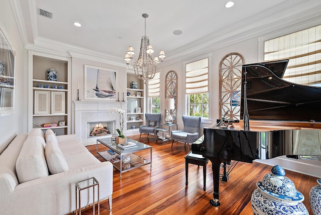 sitting room featuring built in features, hardwood / wood-style flooring, a notable chandelier, and ornamental molding