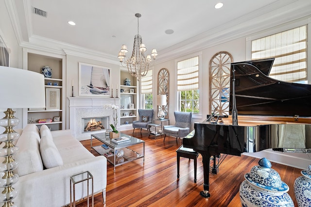 living room with a notable chandelier, wood-type flooring, built in features, and crown molding