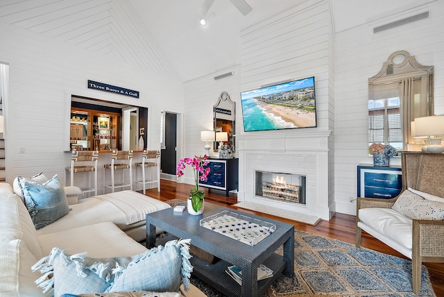 living room featuring wood-type flooring, high vaulted ceiling, and a fireplace