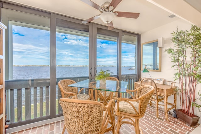 sunroom featuring ceiling fan and a water view