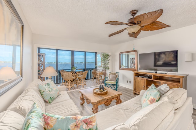 living room with ceiling fan, hardwood / wood-style floors, and a textured ceiling