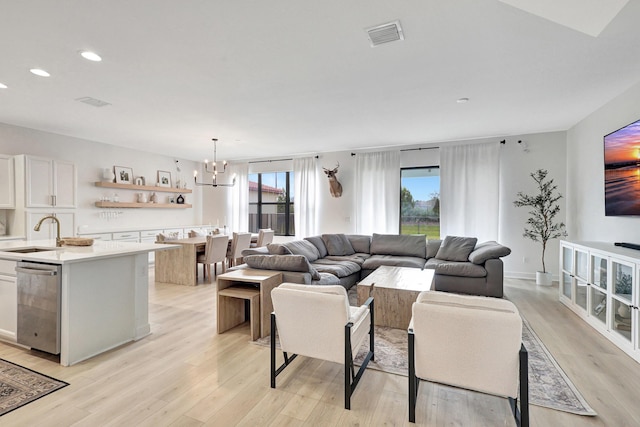 living room featuring a chandelier, light hardwood / wood-style flooring, and sink