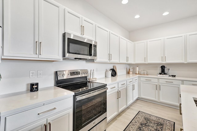 kitchen with appliances with stainless steel finishes, light hardwood / wood-style flooring, and white cabinets