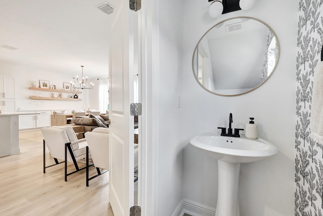 bathroom with hardwood / wood-style flooring and an inviting chandelier