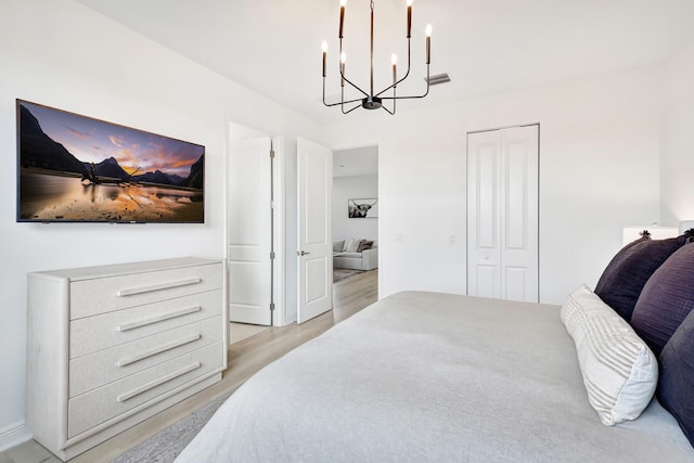 bedroom featuring a closet, light hardwood / wood-style floors, and an inviting chandelier