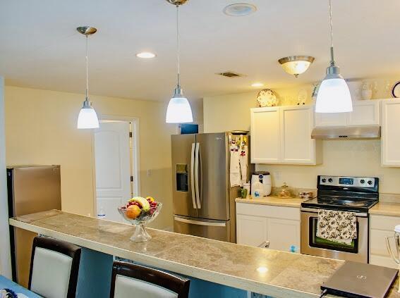 kitchen with white cabinets, appliances with stainless steel finishes, and pendant lighting