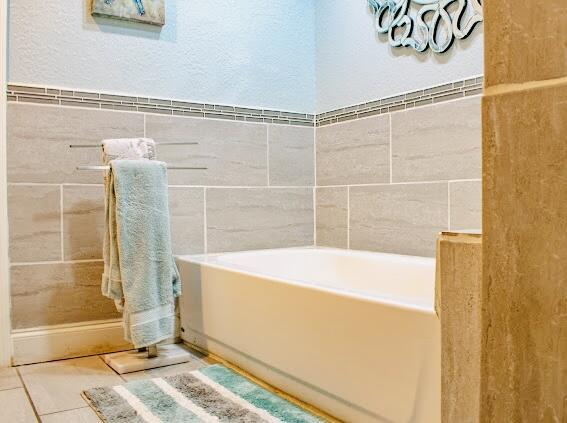 bathroom with tile patterned floors and a washtub