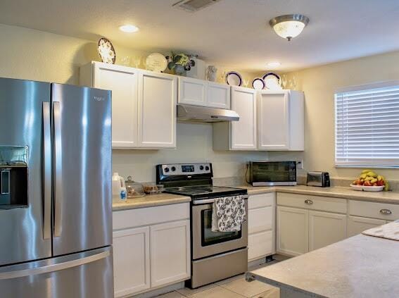 kitchen with white cabinets, appliances with stainless steel finishes, and light tile patterned flooring