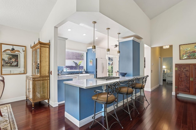 kitchen featuring vaulted ceiling, a kitchen breakfast bar, hanging light fixtures, kitchen peninsula, and paneled refrigerator